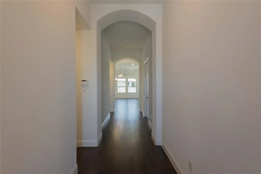 Arches in the foyer featuring dark wood-finish flooring, white baseboards, and arched doorways