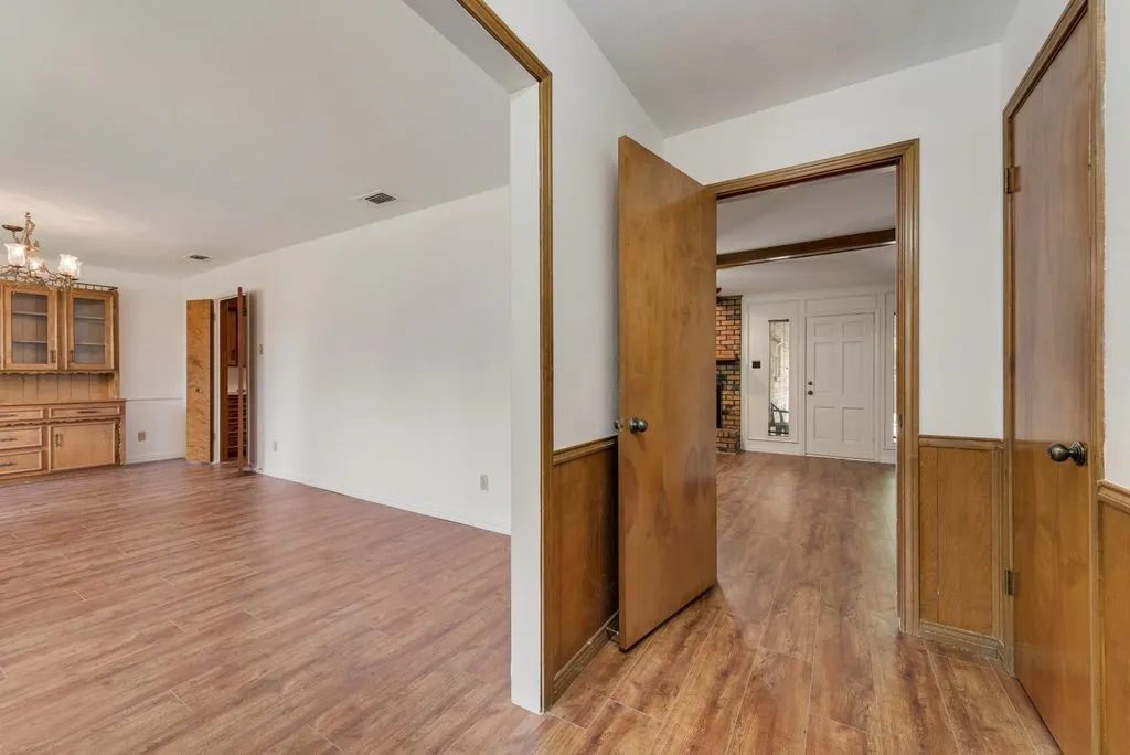 Room featuring wood-finish flooring, white walls, and a built-in wooden hutch with glass-fronted cabinetry