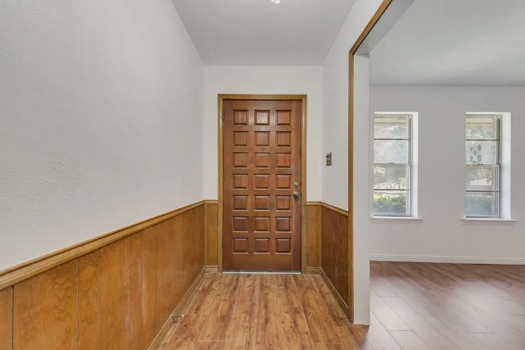 Entryway featuring a paneled wood door, wood-finish flooring, and wood wainscoting
