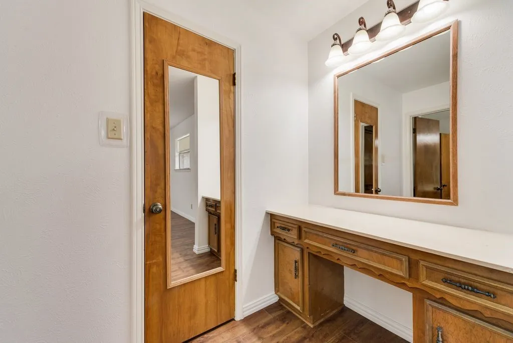 Built-in wood-finish vanity with countertop, framed mirror, and four-light fixture