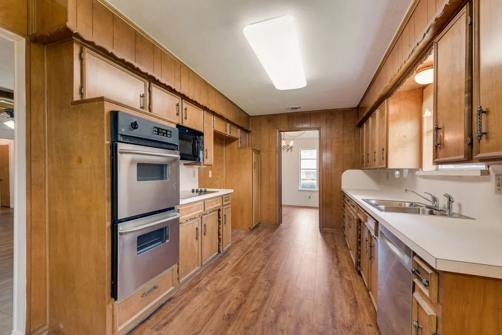 Kitchen featuring wood-finish cabinetry, stainless steel double oven, stainless steel microwave, and white countertops
