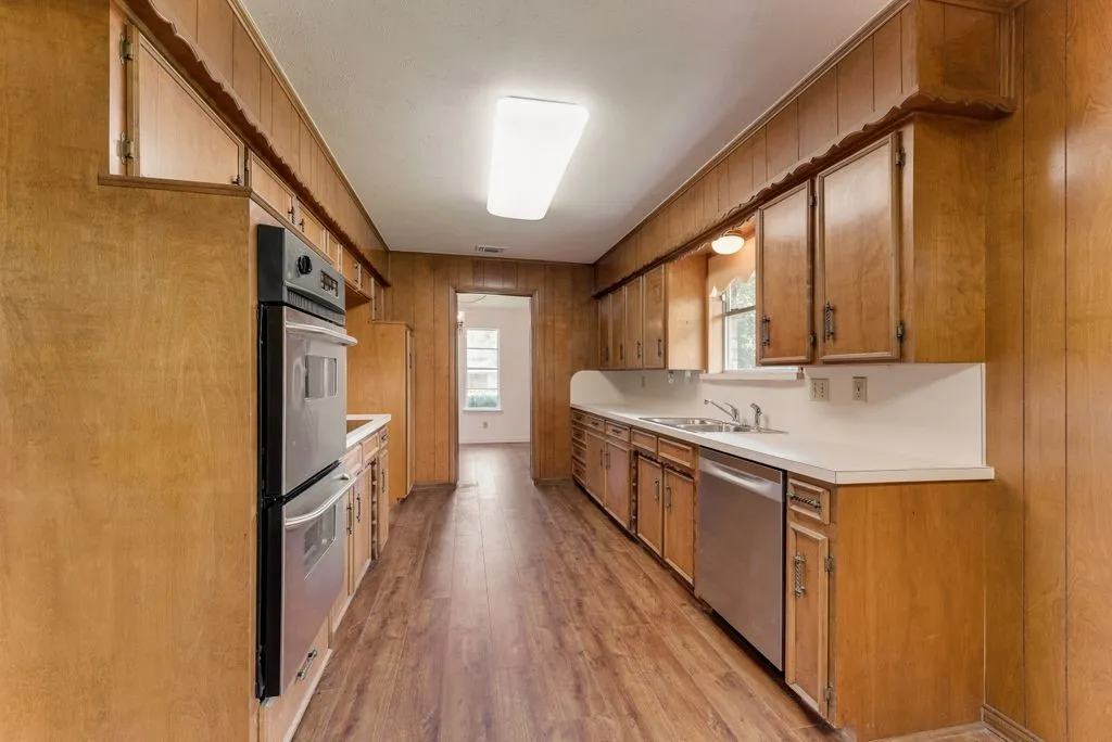 Galley kitchen featuring wood-finish wall paneling and cabinetry