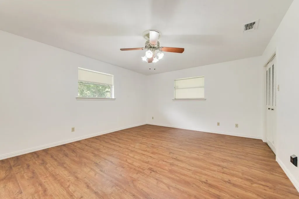 Spacious room featuring wood-finish flooring, white baseboards, and bright white walls