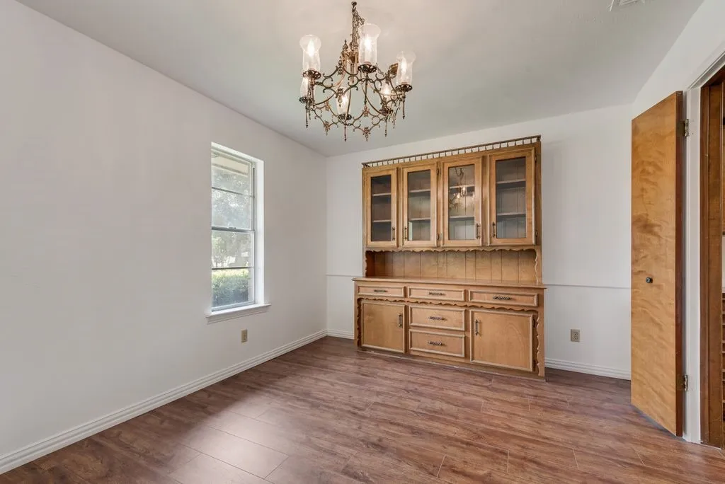 Room featuring a built-in wooden hutch with glass-fronted upper cabinets, wood-finish flooring, and a single window