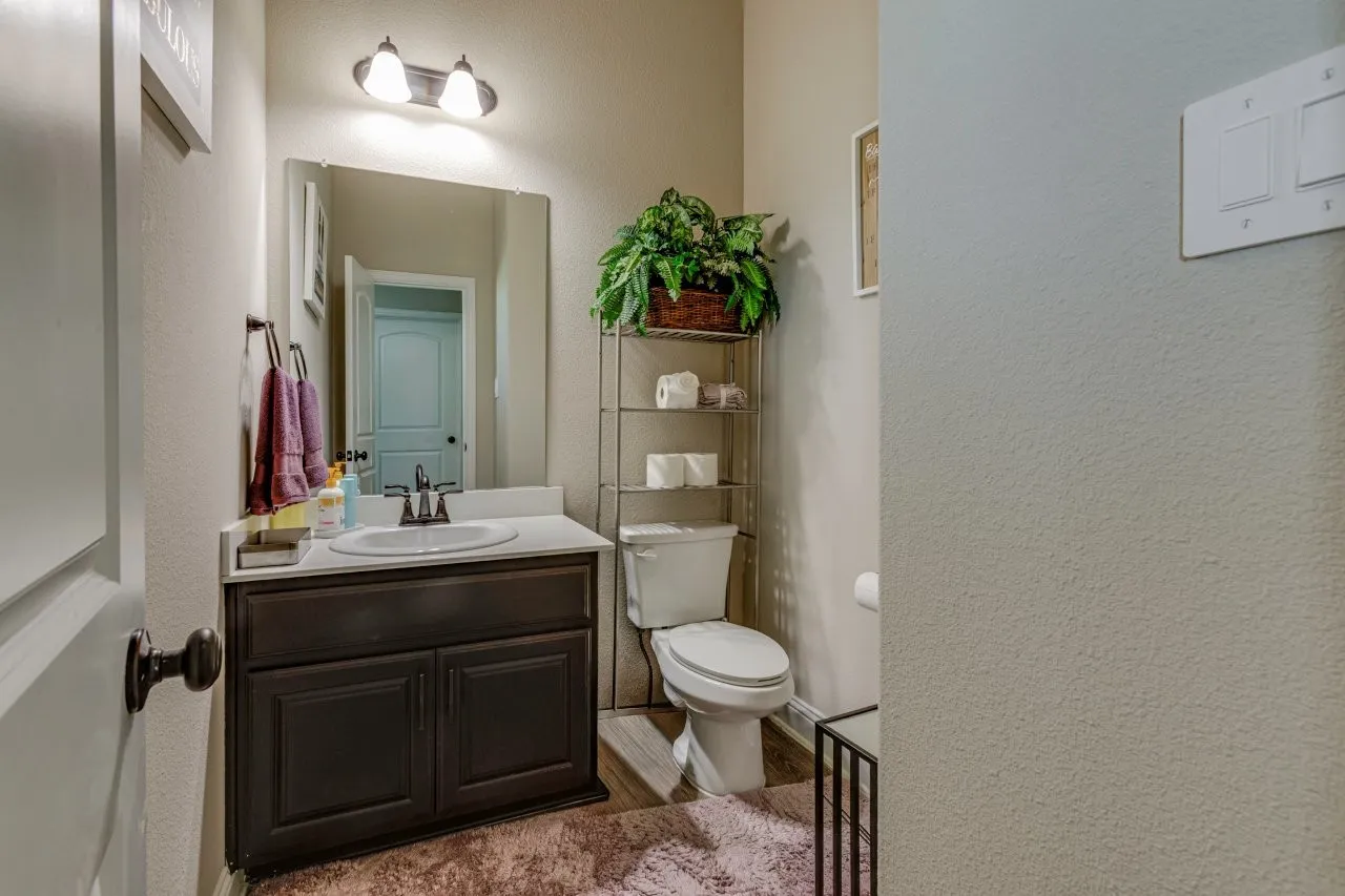Powder room featuring a dark wood-finish vanity with an integrated sink, polished chrome faucet, and a wall-mounted mirror