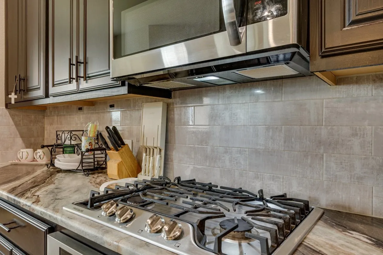 Built-in gas range with stainless steel hardware, set into a stone countertop featuring natural veining