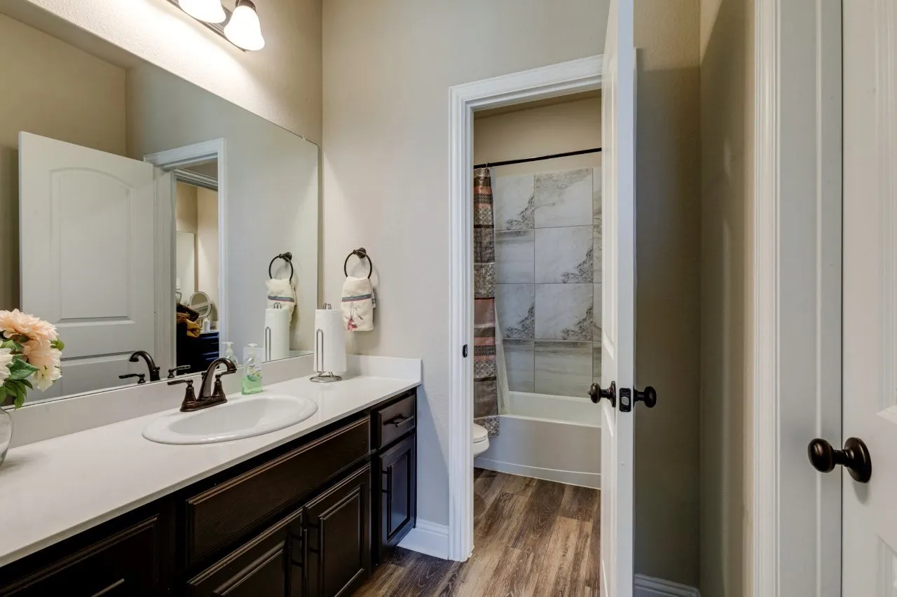 Bathroom vanity featuring an integrated sink, dark wood cabinetry, white countertop, and wood-finish flooring