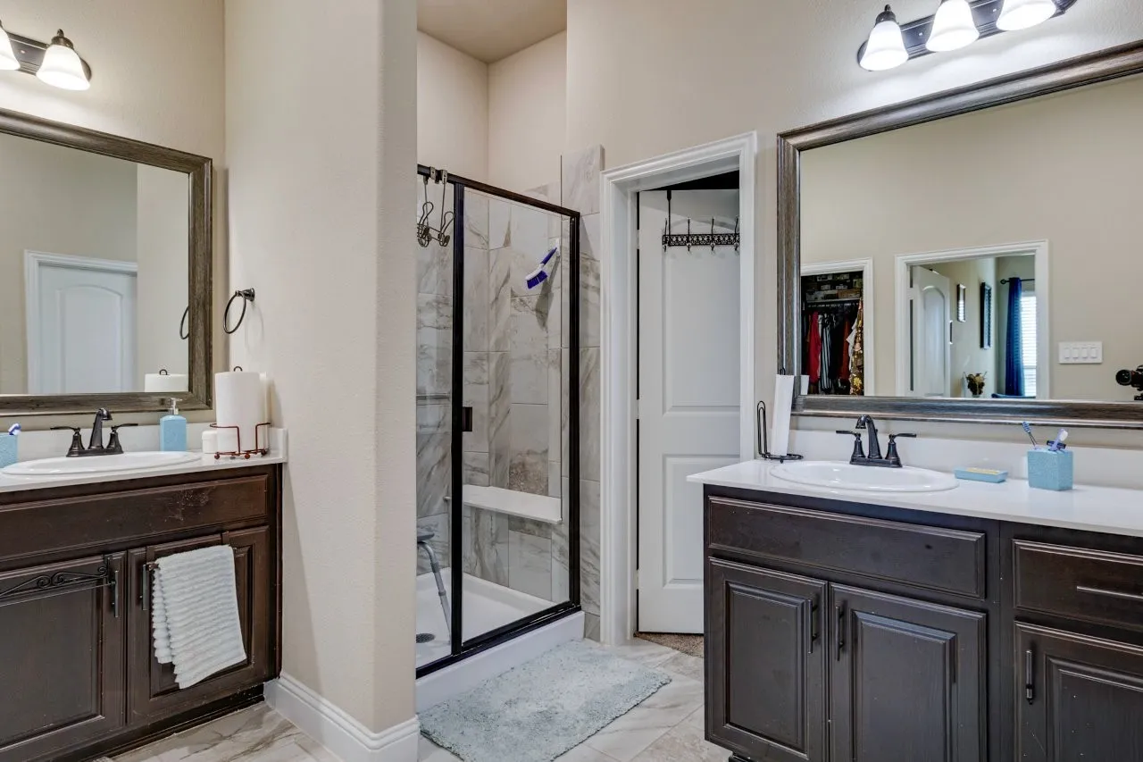 Dual vanity bathroom featuring dark wood cabinetry, white countertops, and framed mirrors