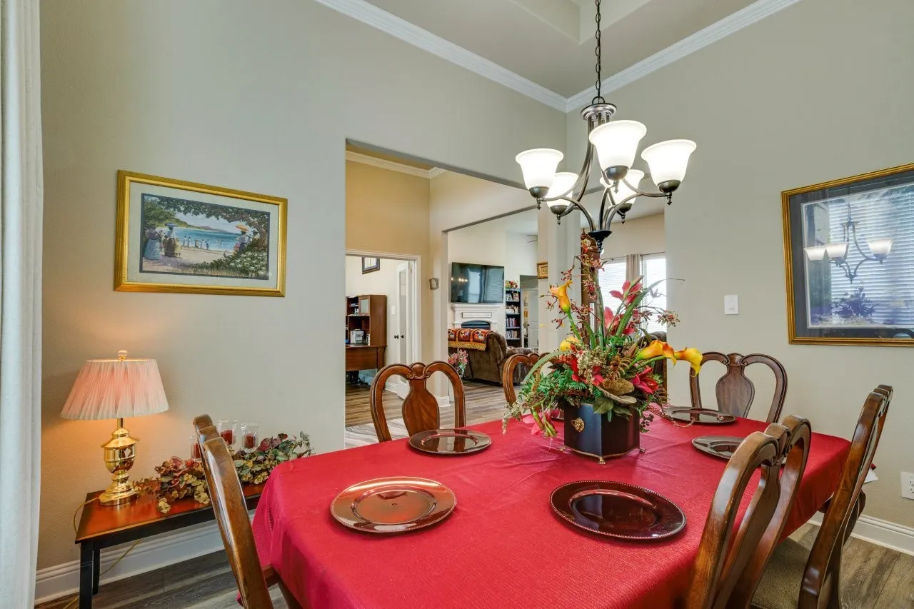 Formal dining area featuring a tray ceiling with crown molding, chandelier lighting, and wood-finish flooring