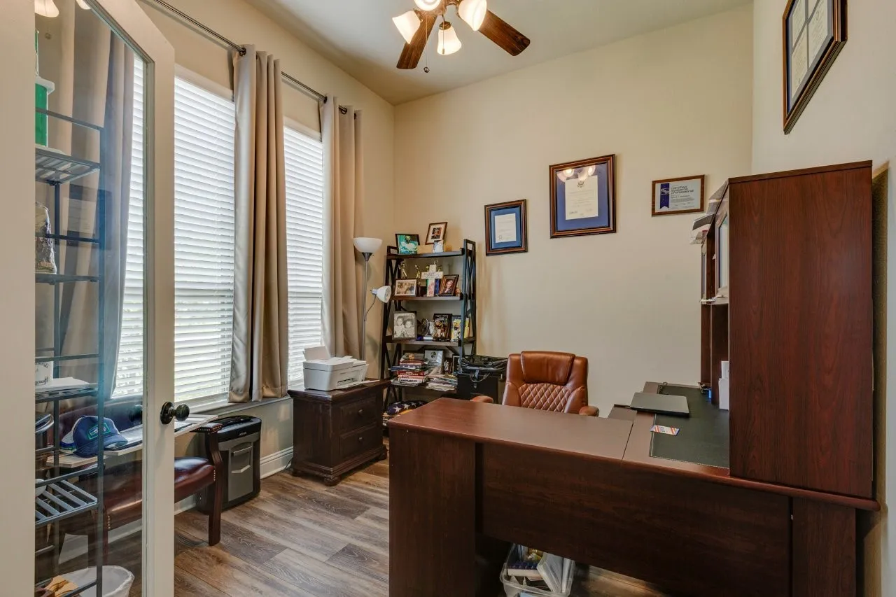 Dedicated office space featuring wood-finish flooring, tall ceilings, and a ceiling fan with integrated lighting
