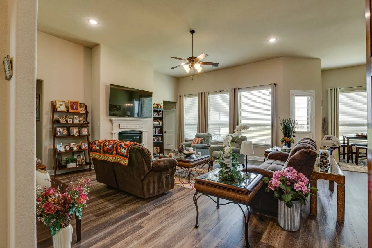 Spacious living area featuring wood-finish flooring, a ceiling fan, recessed lighting, and multiple windows with blinds