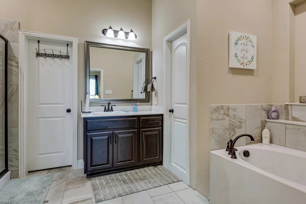 Bathroom vanity with a dark wood-finish base cabinet, white countertop, and framed mirror