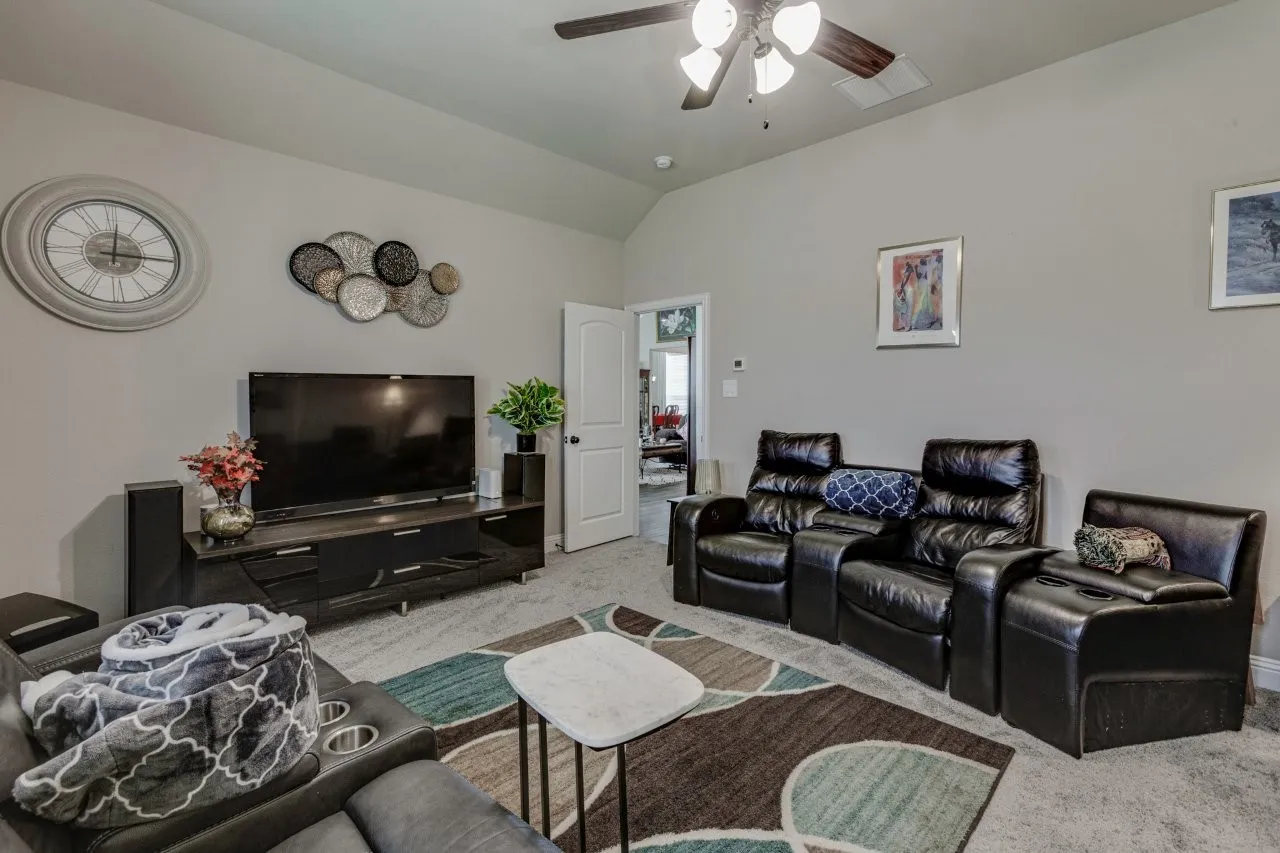Spacious room featuring vaulted ceilings, ceiling fan, and carpeted flooring