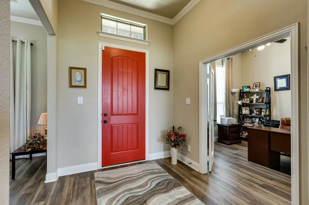 Entryway featuring a vibrant red paneled door with an overhead transom window