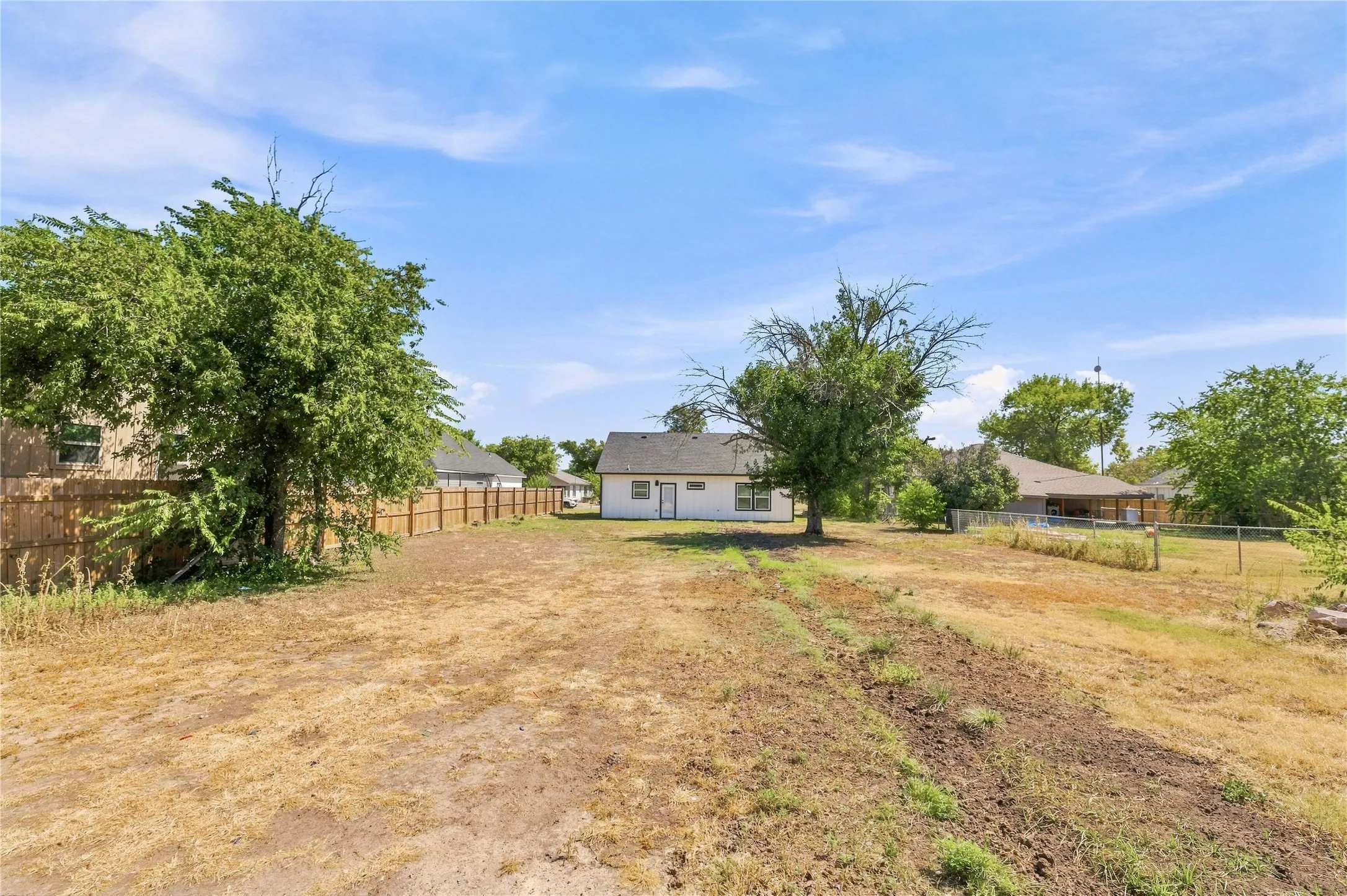 Expansive backyard with a wood-fenced perimeter and mature trees