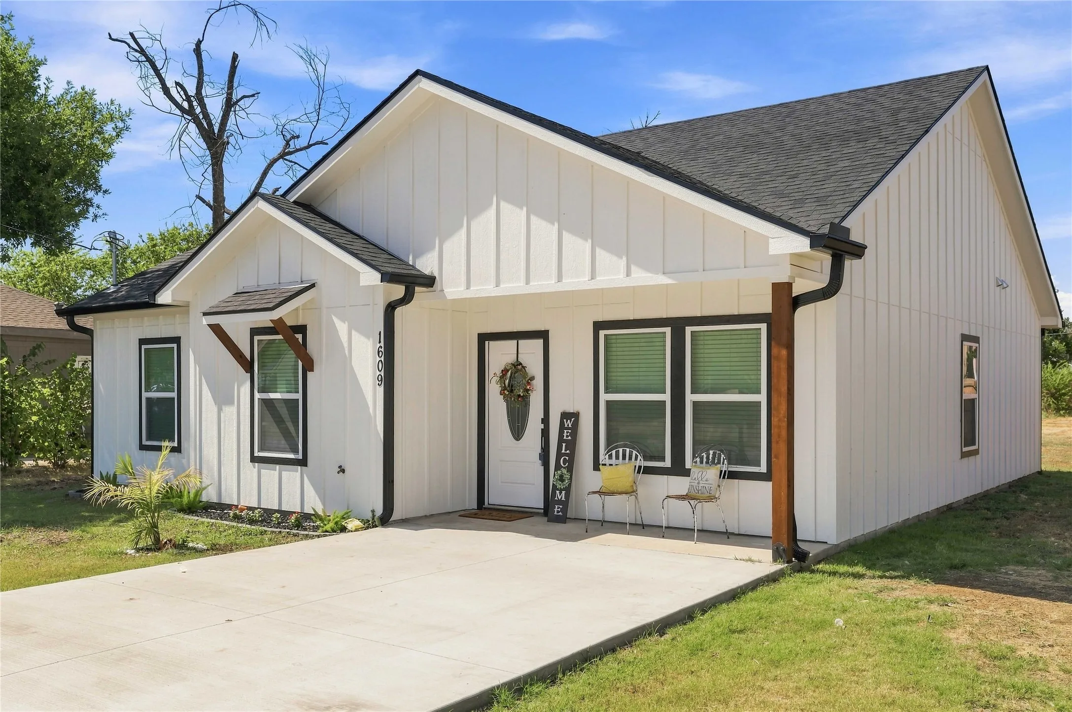 Contemporary exterior with vertical panel siding, dark-framed windows, a covered entry, and a concrete driveway