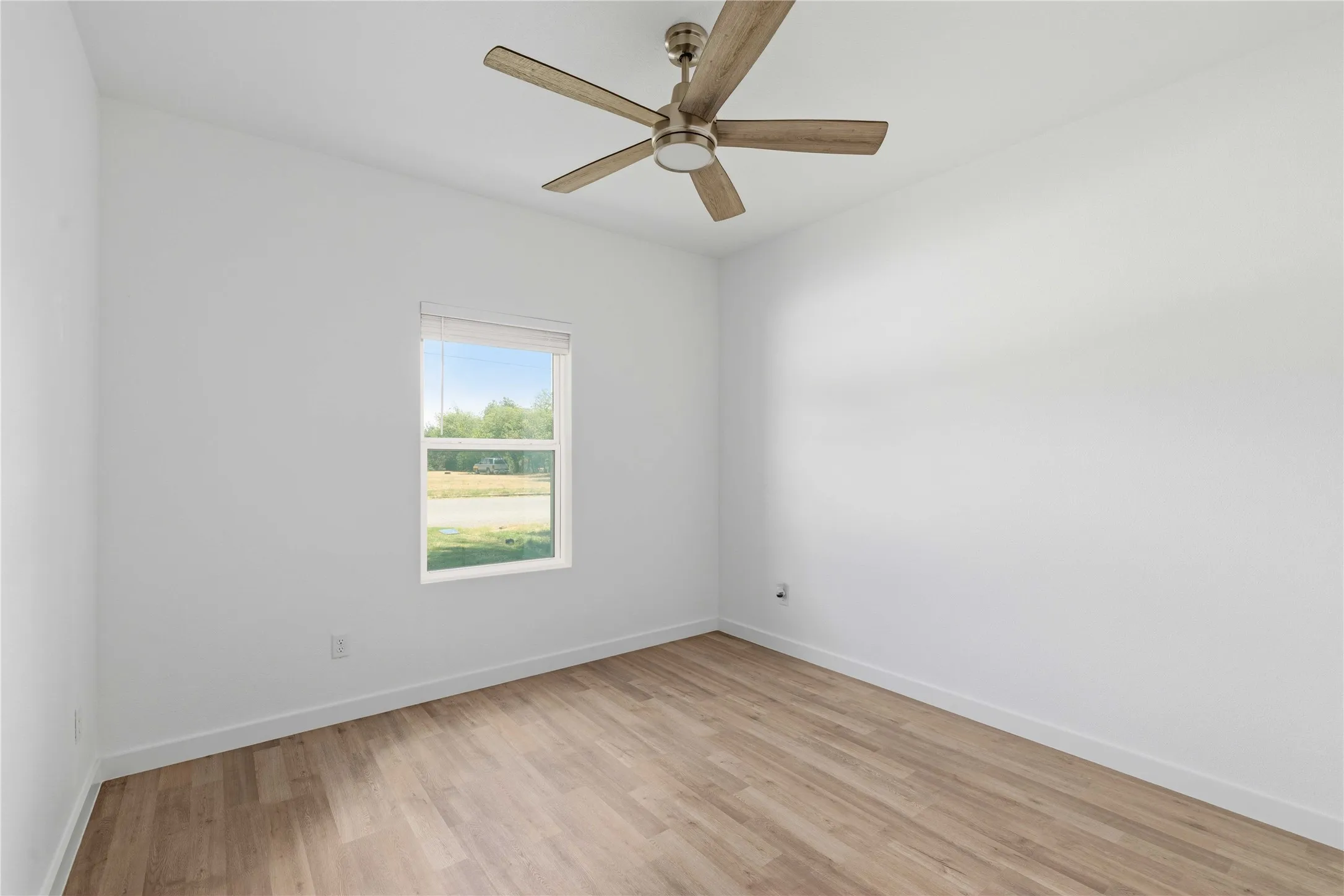 Recessed window with blinds, wood-finish flooring, and a ceiling fan with integrated lighting