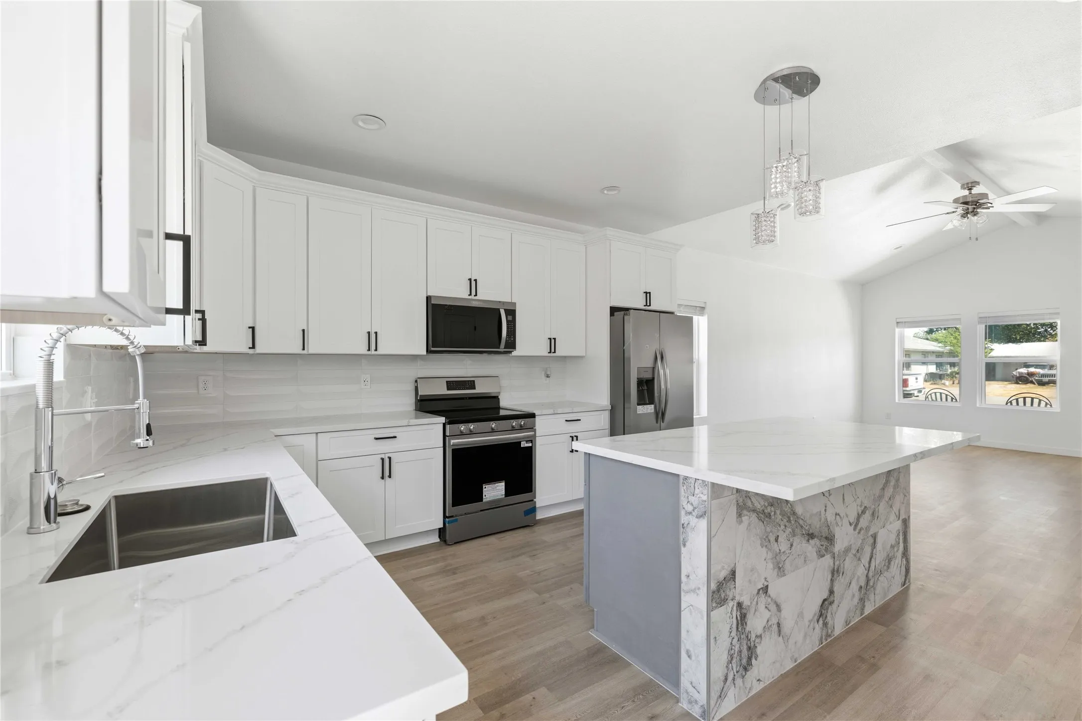 Kitchen featuring white cabinetry, stainless steel appliances, a center island with a waterfall countertop, and wood-finish flooring