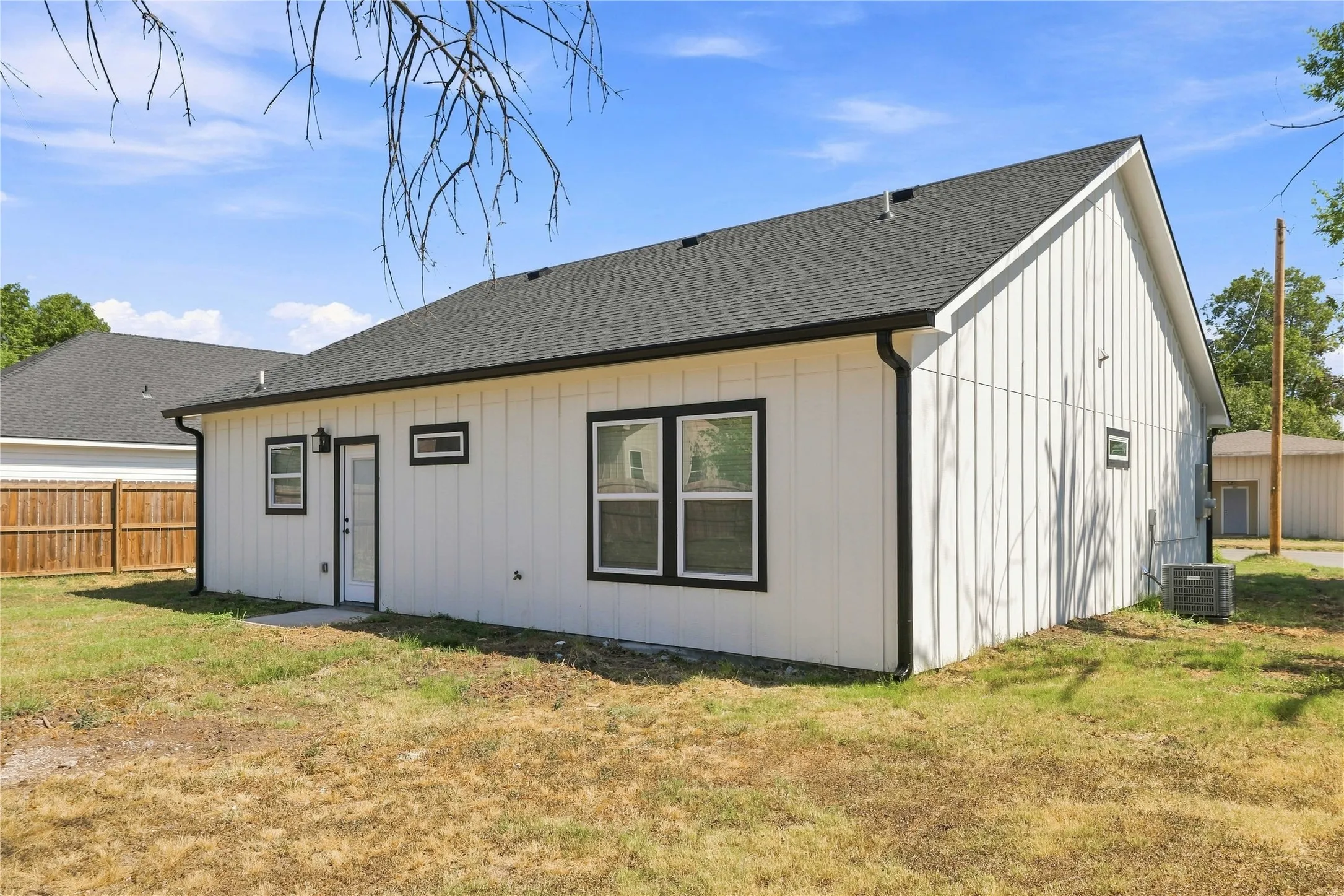 White vertical siding exterior with contrasting dark trim, dark shingle roof, and exterior lighting fixture