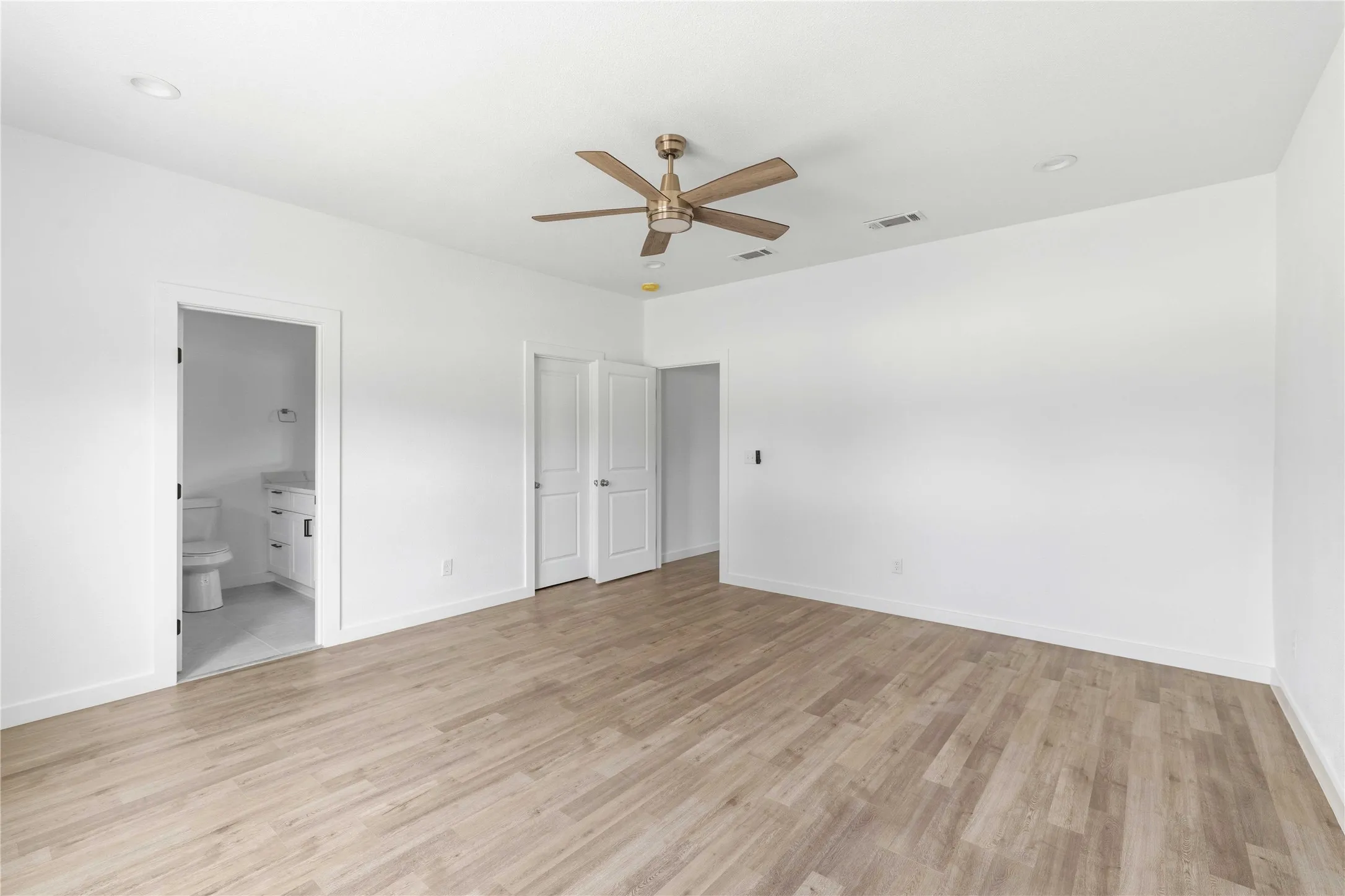 Spacious room featuring light wood-finish flooring, recessed lighting, and a ceiling fan
