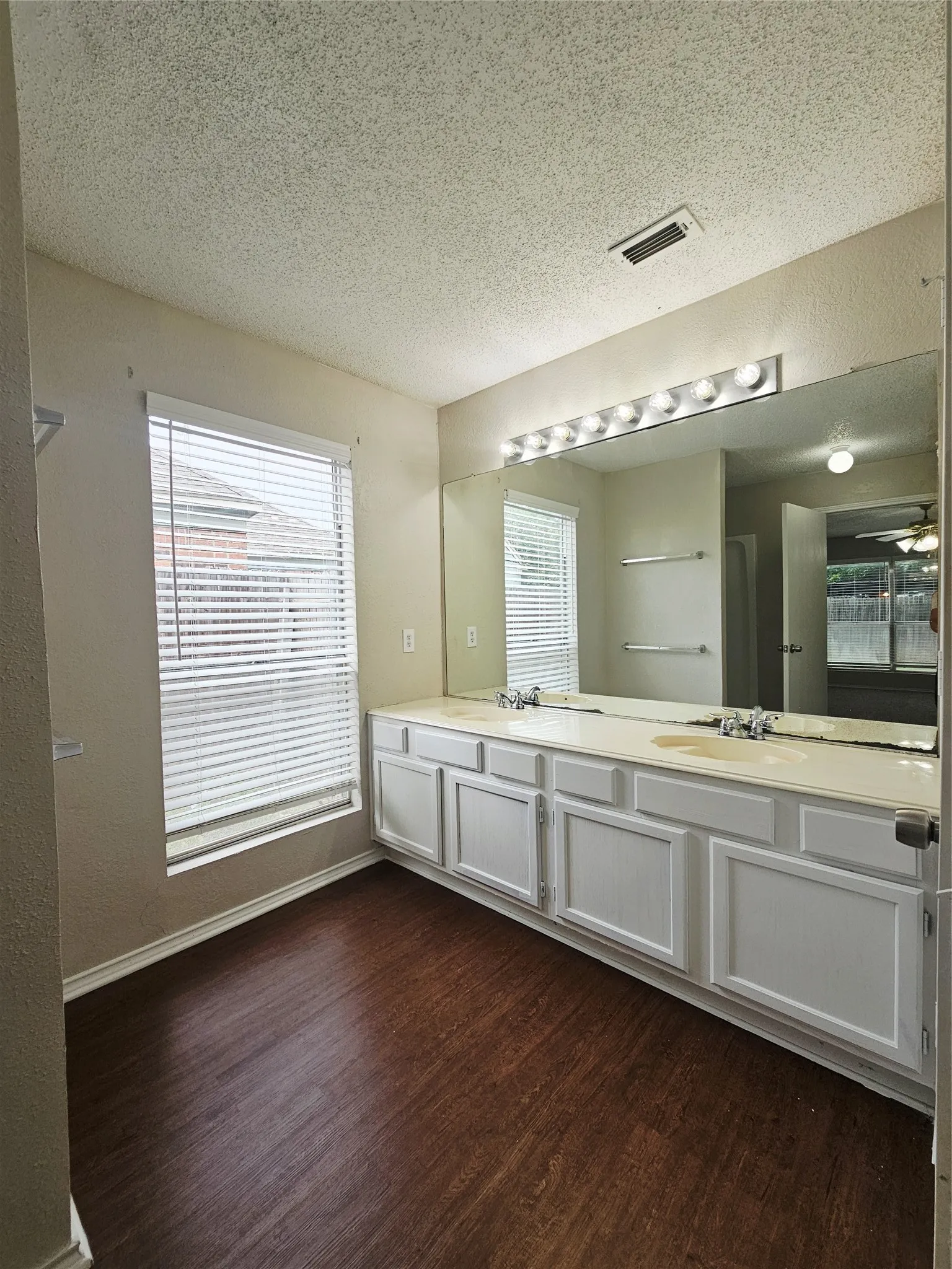 Bathroom featuring a dual vanity with white cabinetry, light-colored countertops, and two integrated sinks
