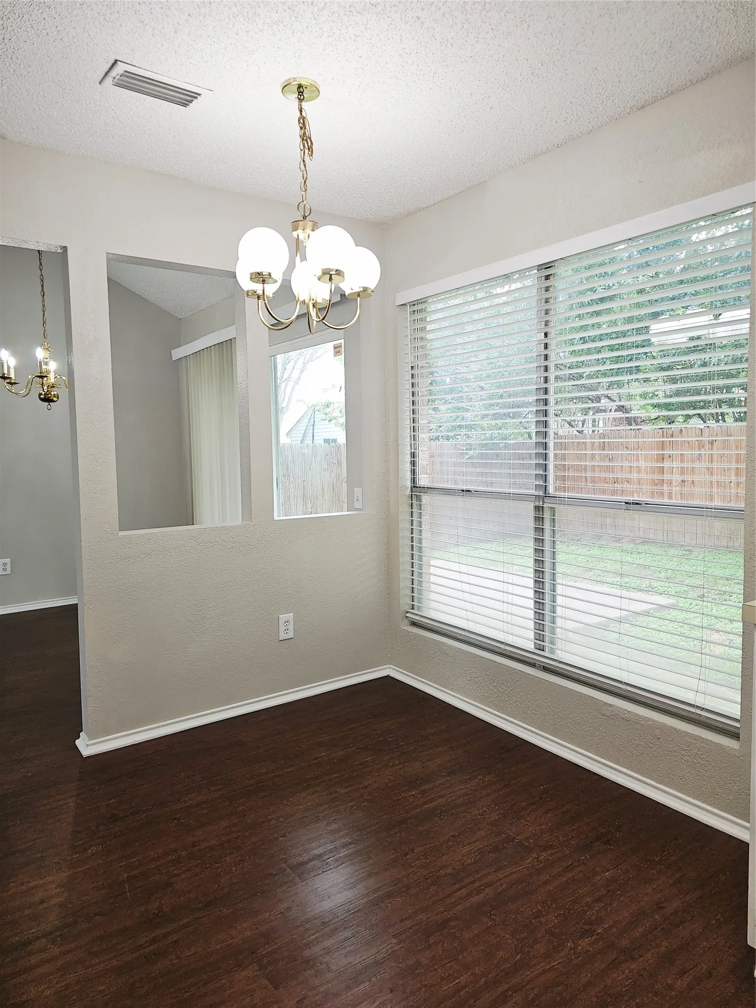 Dining area featuring dark wood-finish flooring and a brass chandelier with frosted glass globes
