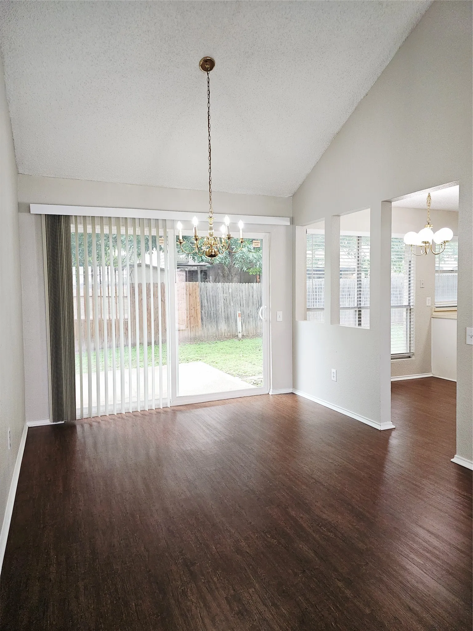 Dining area featuring wood-finish flooring, a vaulted ceiling, and an ornate chandelier
