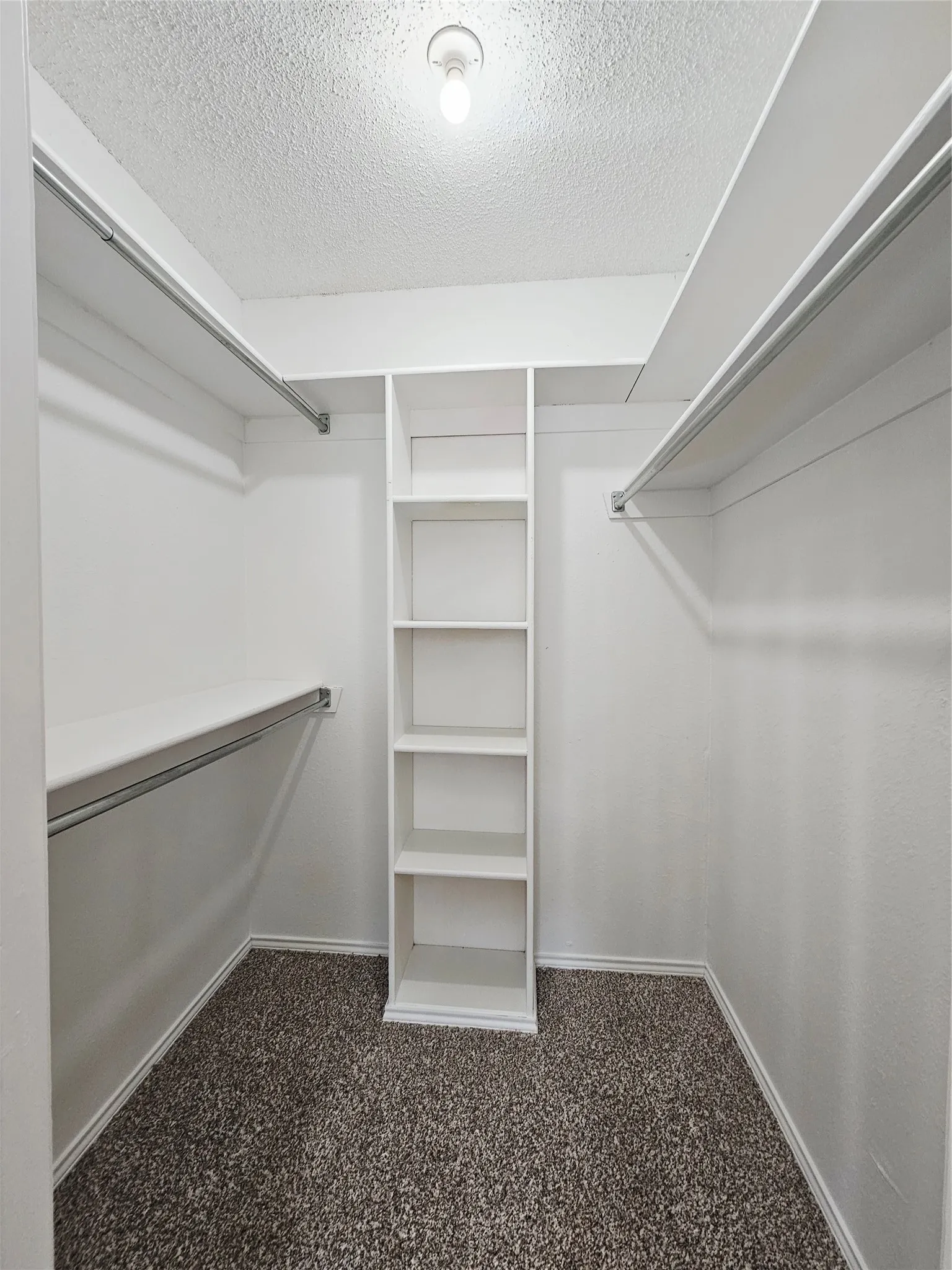 Walk-in closet featuring built-in shelving, multiple hanging rods, white walls, and carpeting