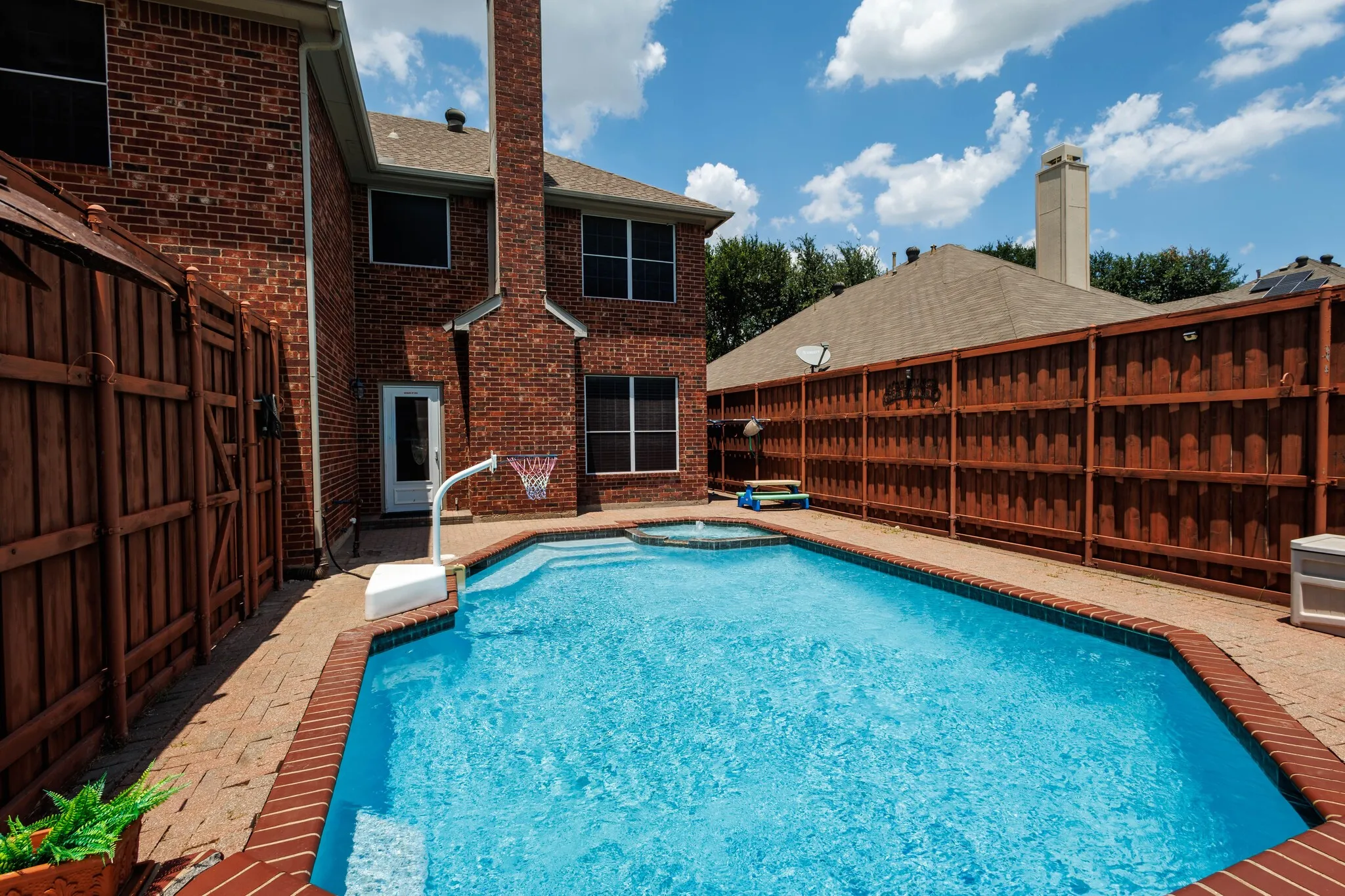 Backyard with a blue-tiled swimming pool and integrated spa