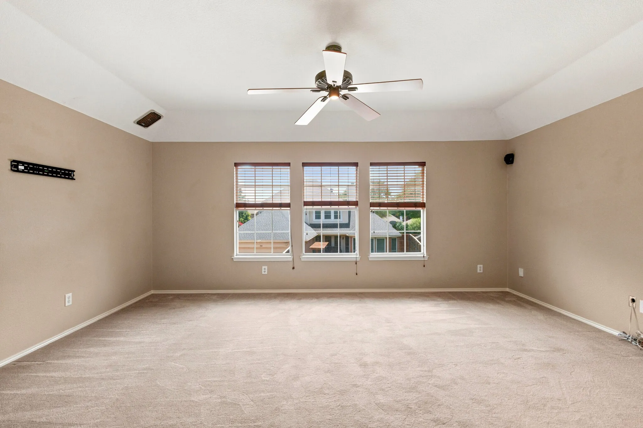 Spacious room with tray ceiling, neutral carpet, and three windows featuring blinds