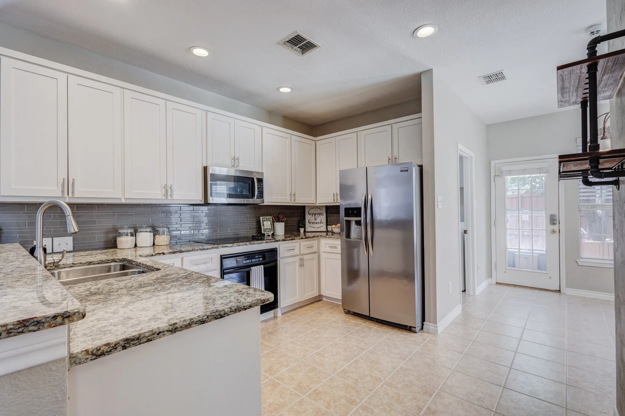 Kitchen featuring light cabinetry, granite-finish countertops, stainless steel appliances, and a tiled backsplash
