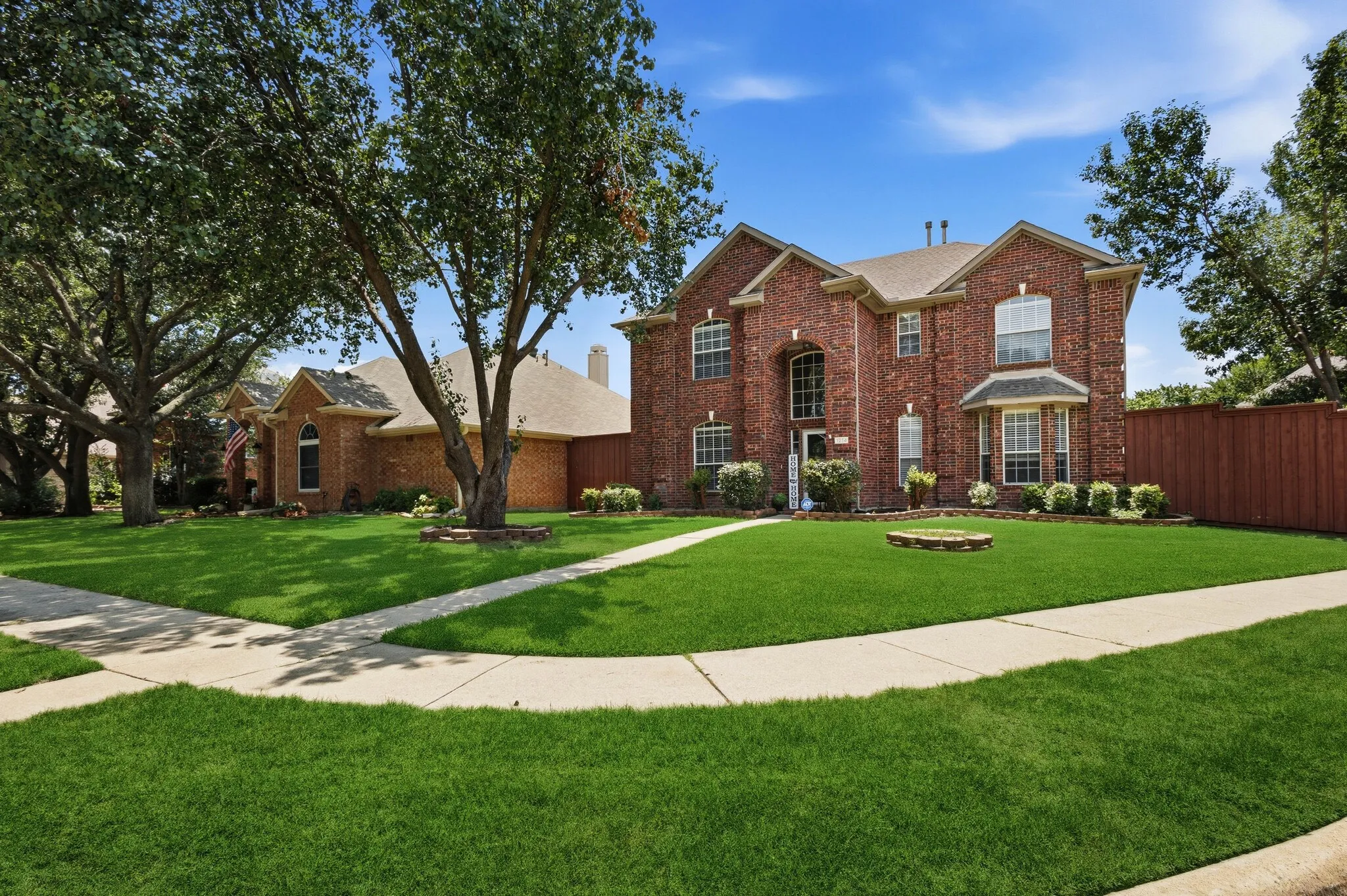 Two-story brick exterior featuring a prominent arched entryway, a bay window with a stone base, and a gabled roofline
