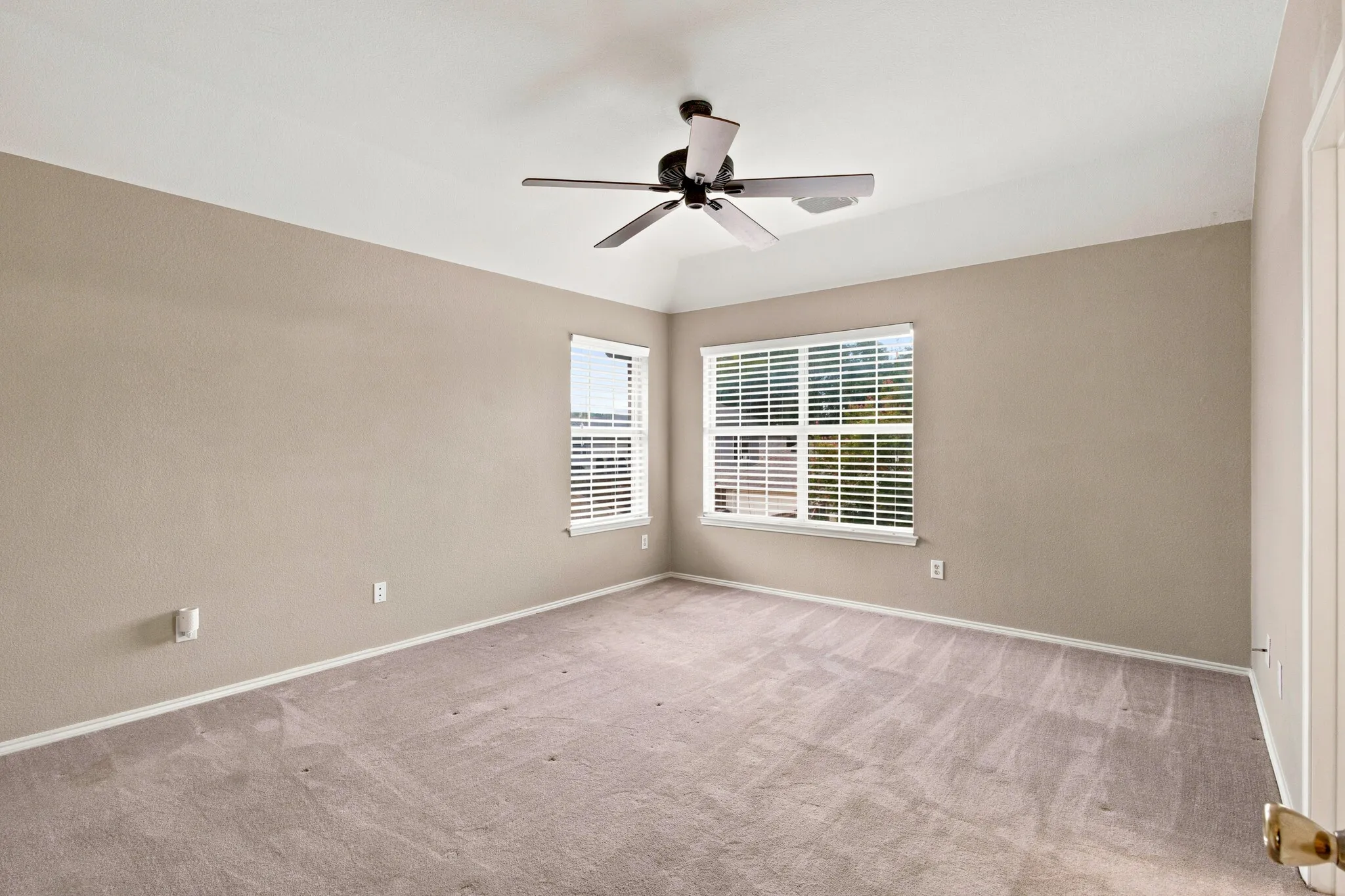 Spacious room featuring vaulted ceilings, light neutral wall paint, and two windows with white blinds