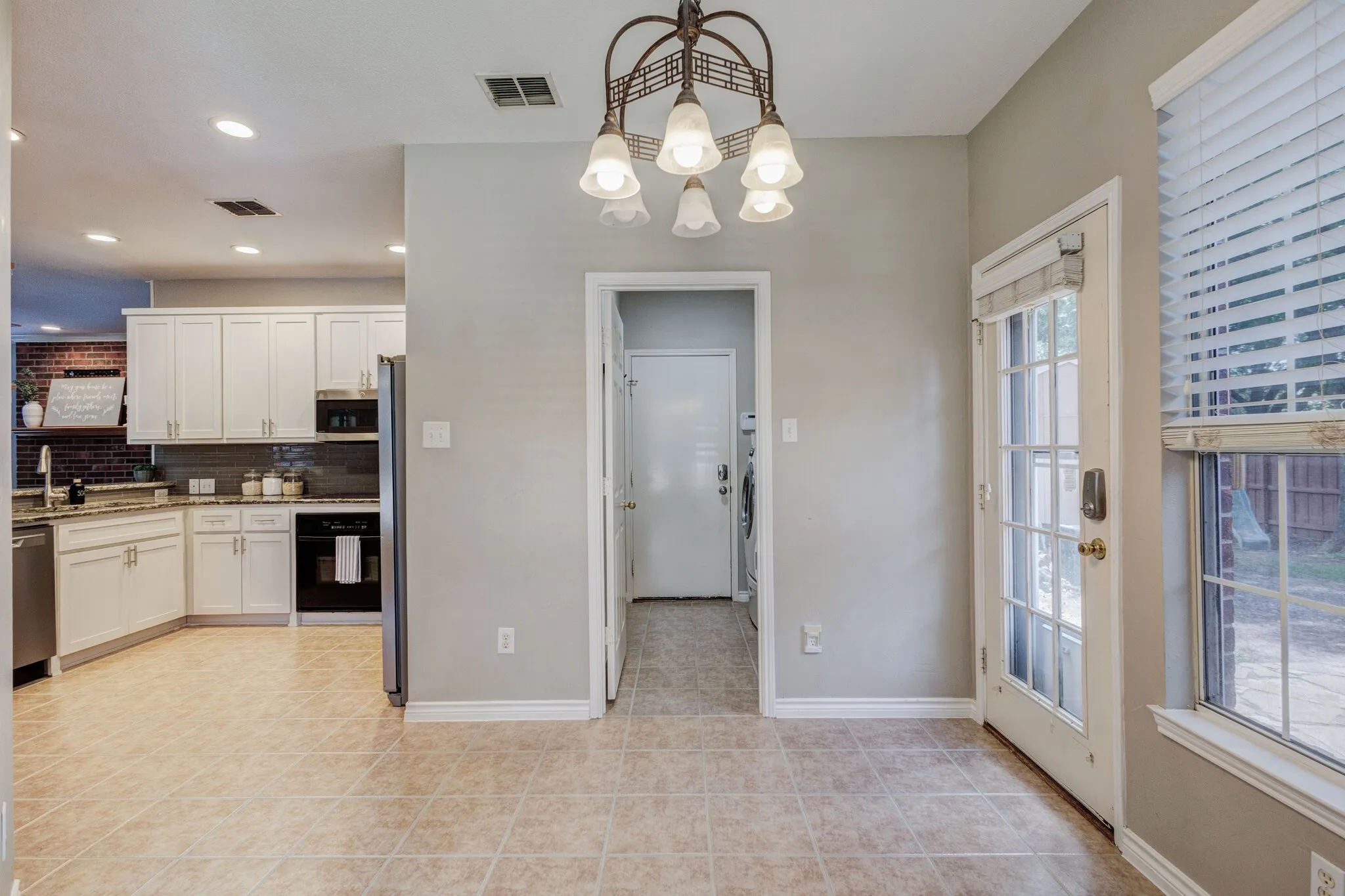 Bright dining area featuring tile flooring, a multi-light chandelier, and a glass-paned exterior door