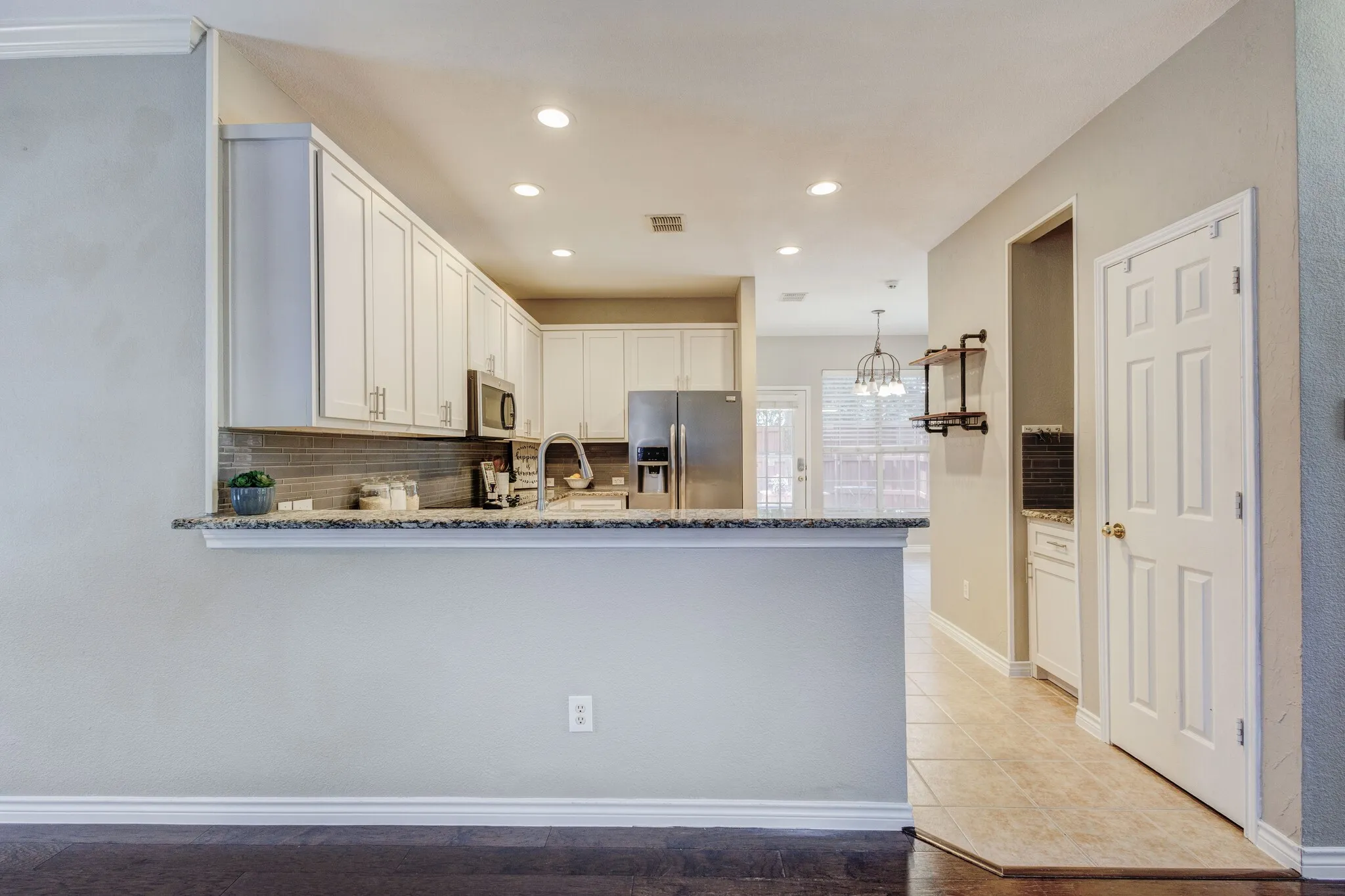 Kitchen featuring white cabinetry, stainless steel appliances, granite countertops, a tile backsplash, and recessed lighting