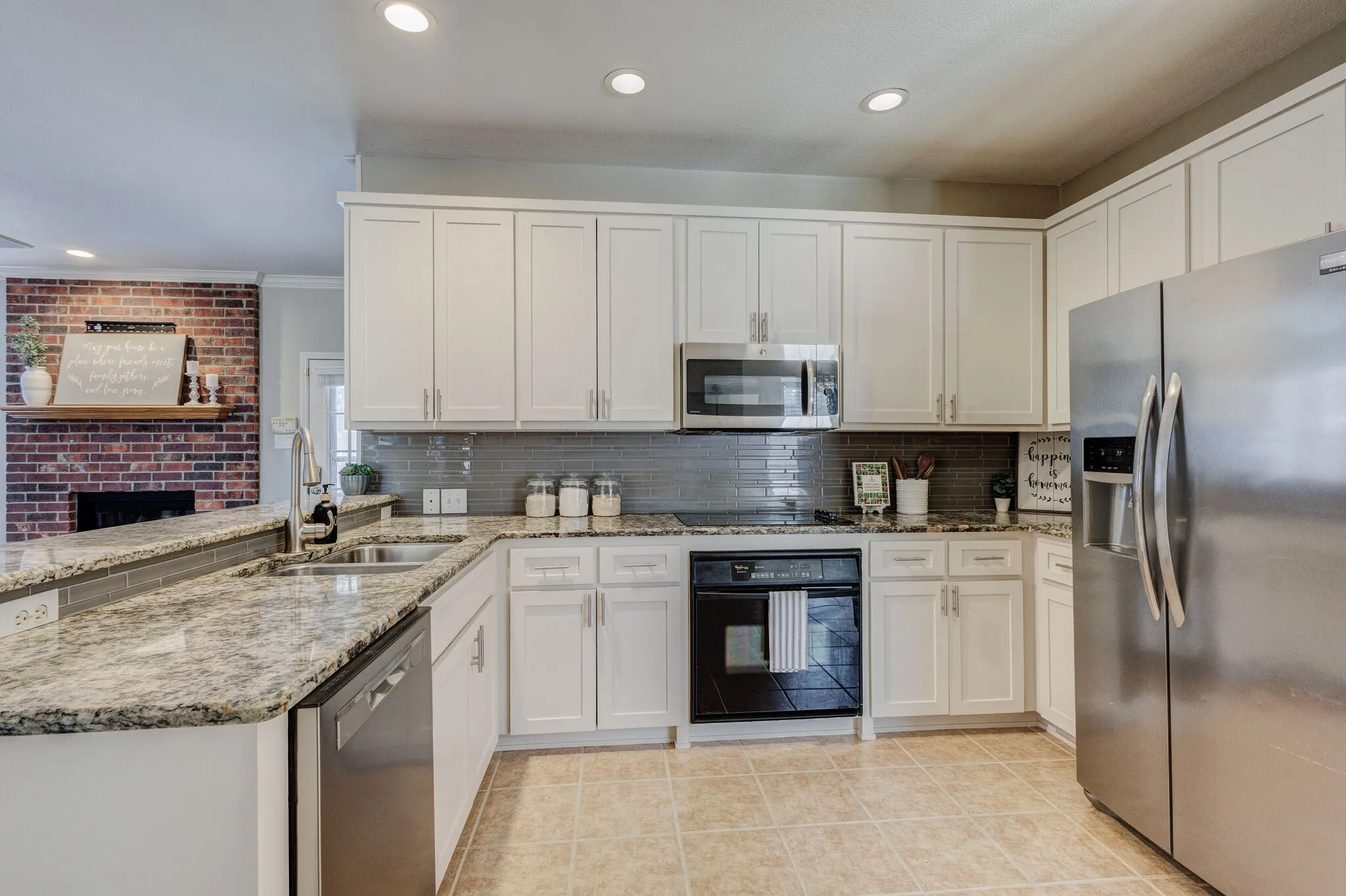 Kitchen featuring white cabinetry, granite countertops, tile backsplash, and stainless steel appliances
