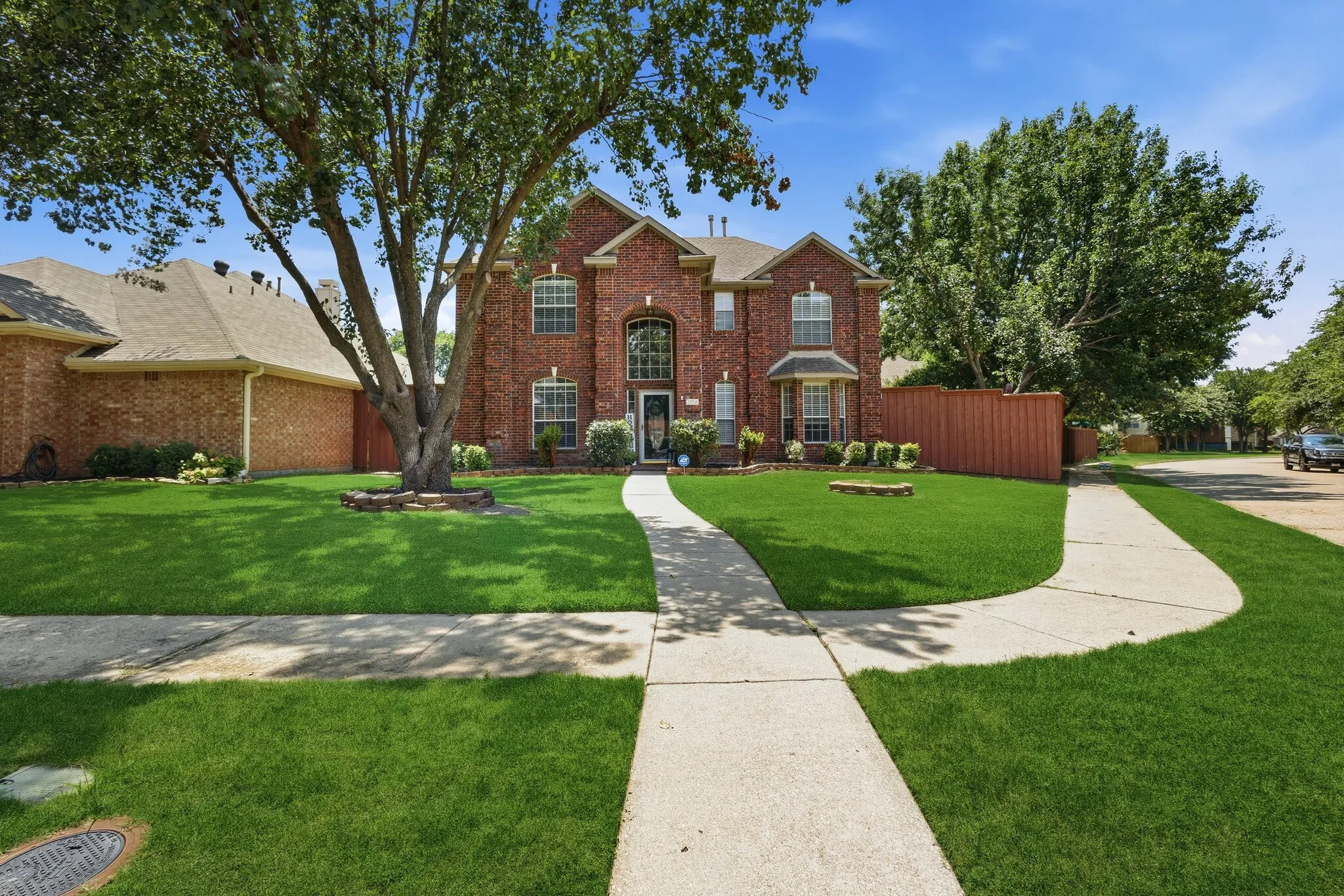 Two-story brick facade residence featuring a prominent mature tree in the front yard