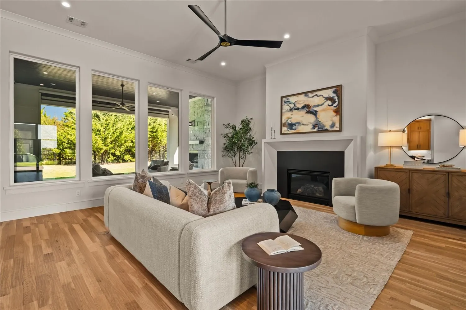Hardwood flooring, high ceilings with recessed lighting, modern ceiling fan, gas fireplace with white mantel, and large picture windows