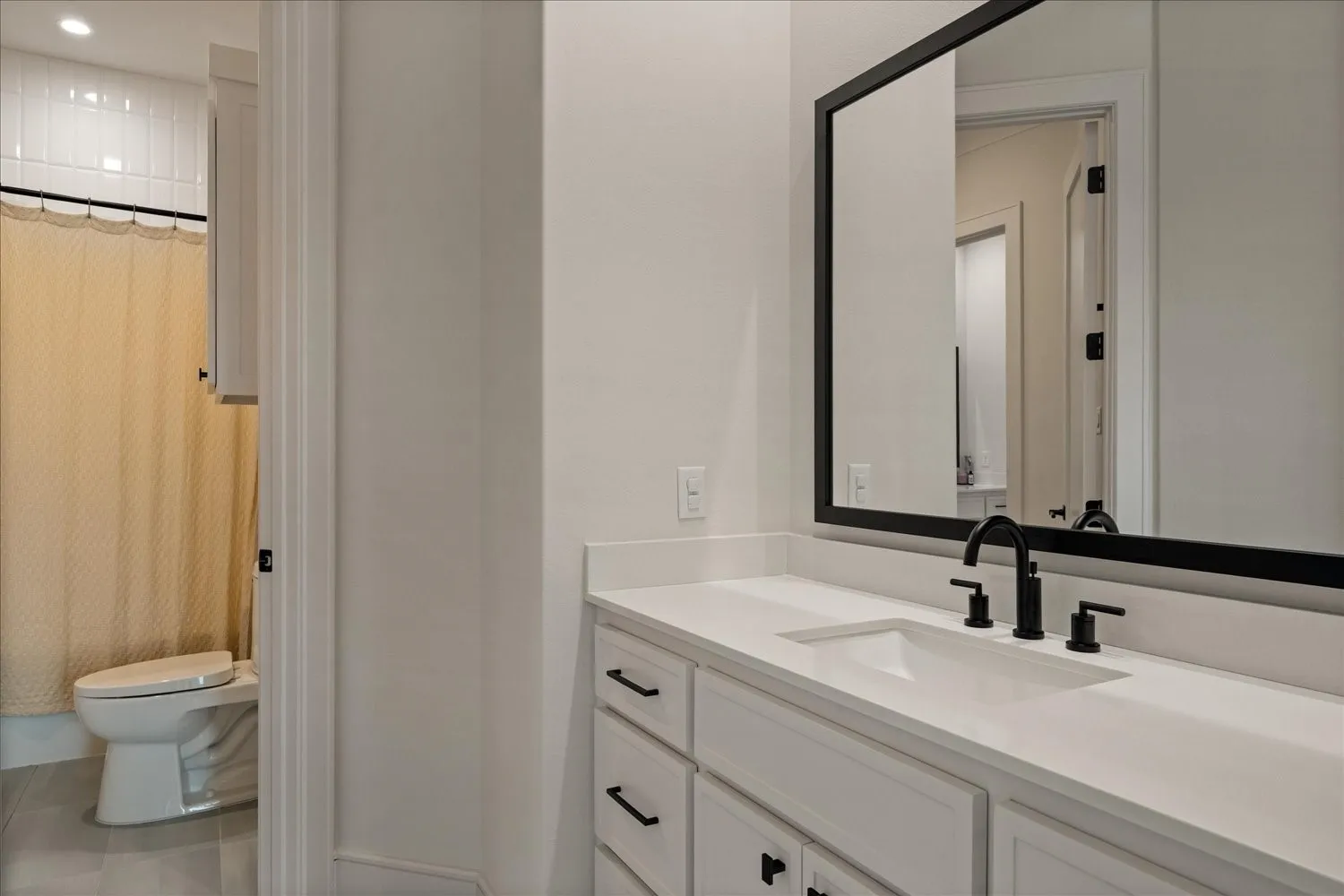 Bathroom vanity featuring a white countertop, undermount sink, and matte black fixtures