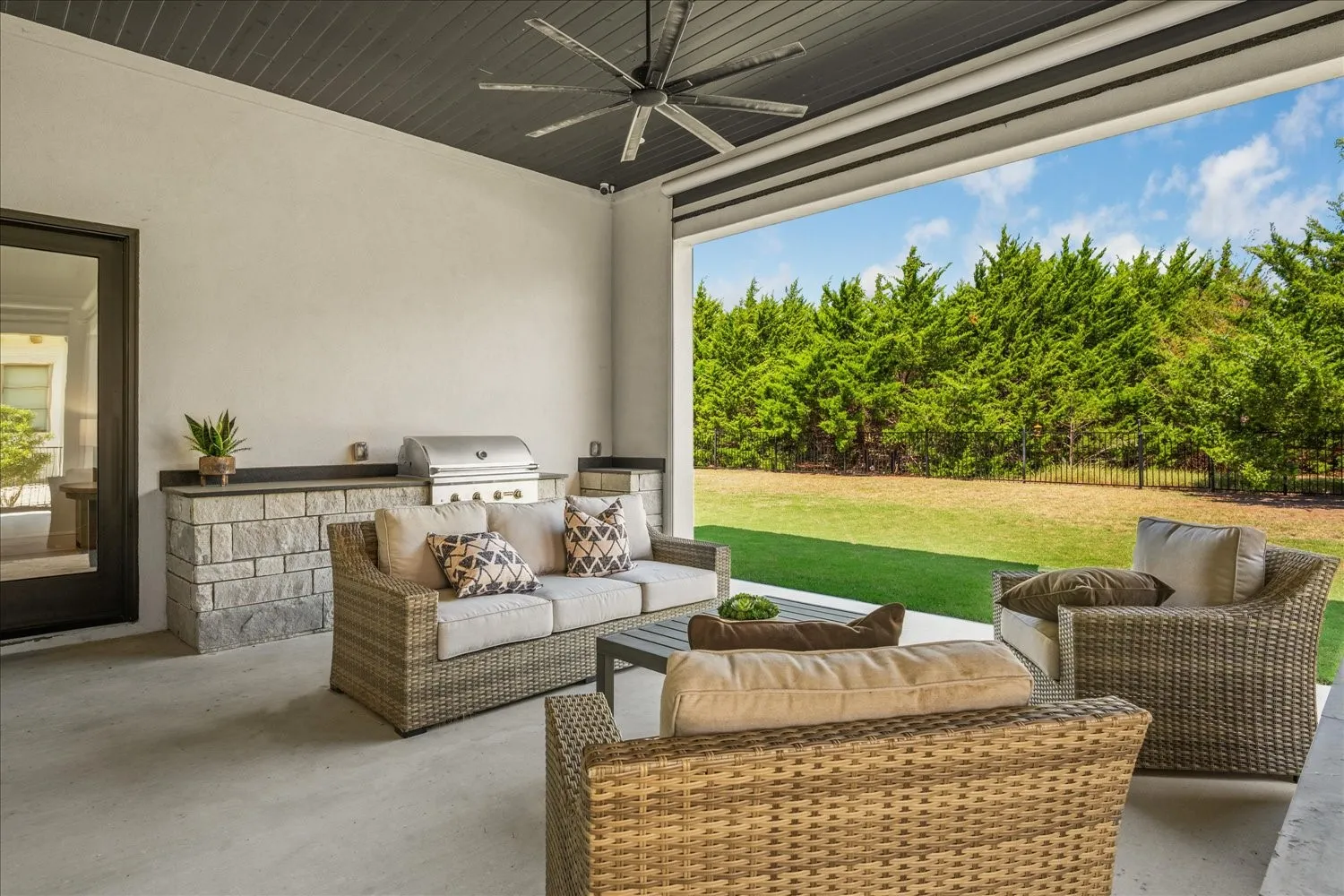 Covered patio with a stone-clad outdoor kitchen, built-in grill, and ceiling fan