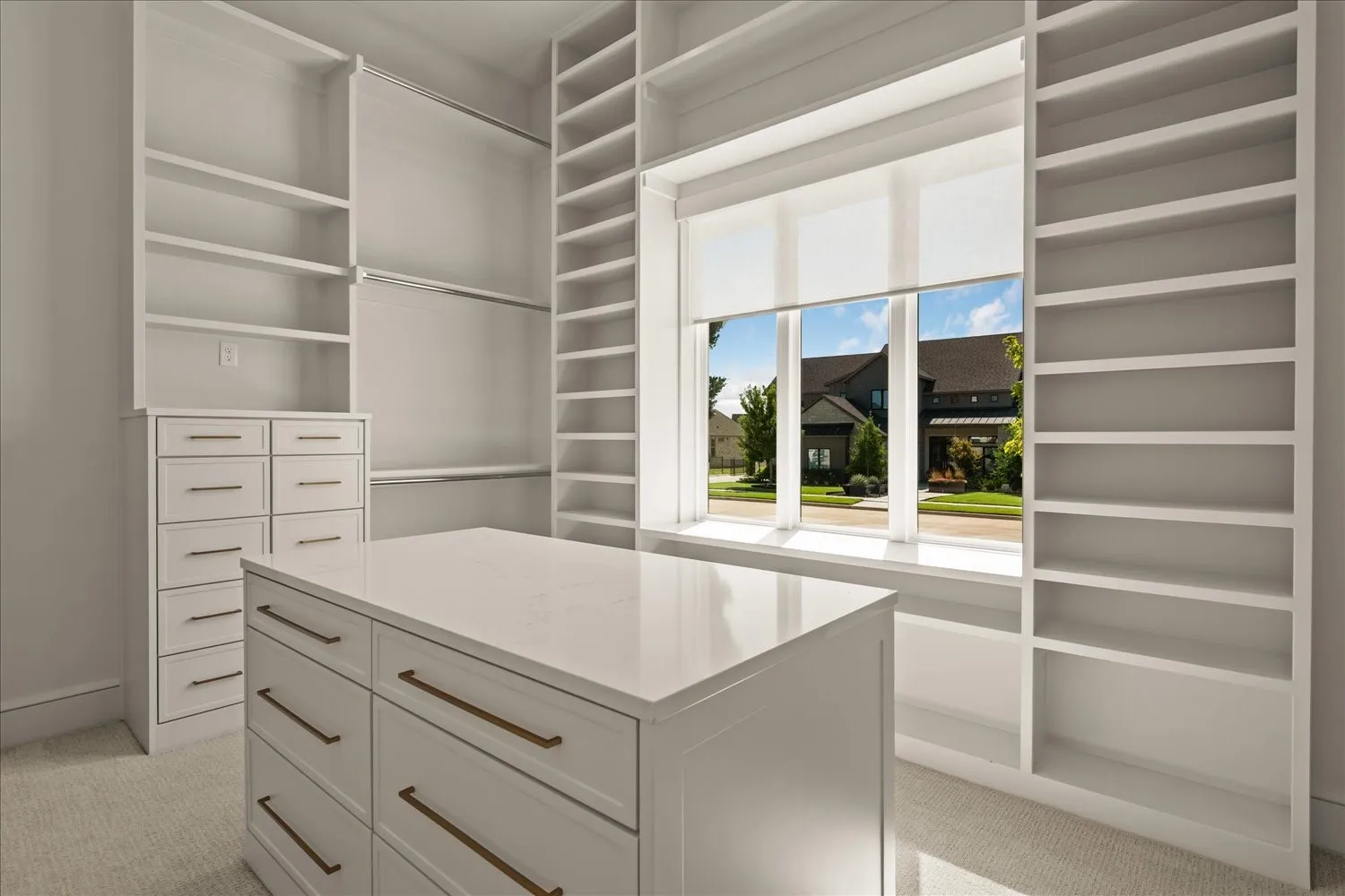 Integrated custom shelving, built-in dresser storage, central island with storage, window with roller shade, and wall-mounted hanging rods