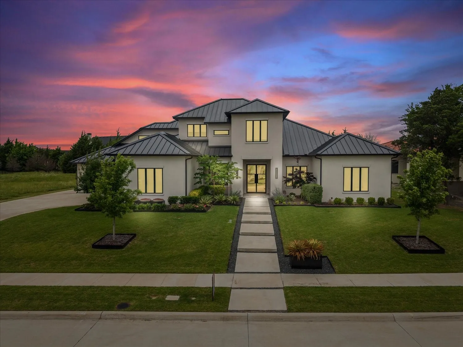 Modern residence featuring a light-toned stucco exterior and a dark metal roof