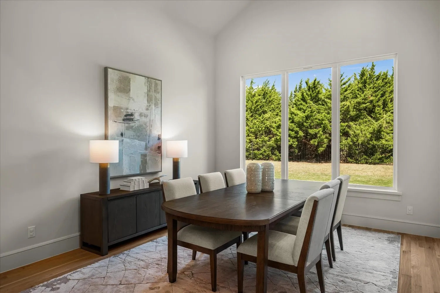 Vaulted ceiling, expansive windows, wood-finish flooring, and a built-in buffet cabinet