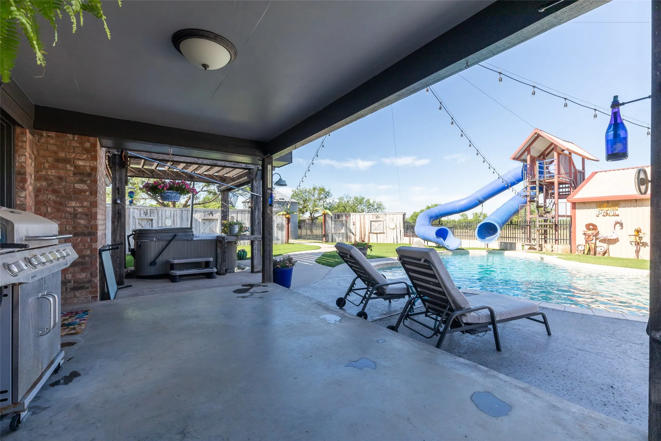 Covered patio with an outdoor kitchen, featuring a built-in grill and brick exterior