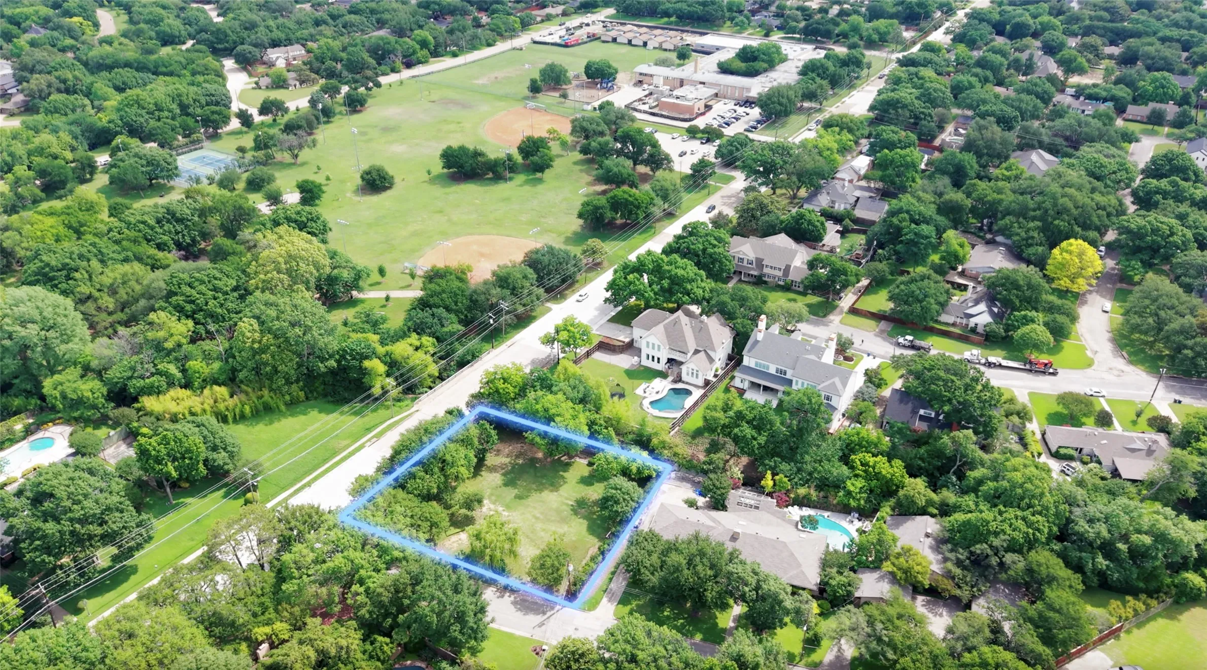 Expansive lot with mature trees and green space, surrounded by established residential properties