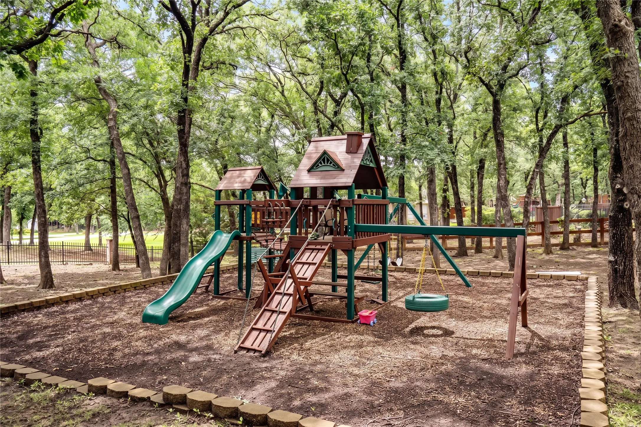 Expansive outdoor play structure featuring a green slide, multiple swings, and a tire swing