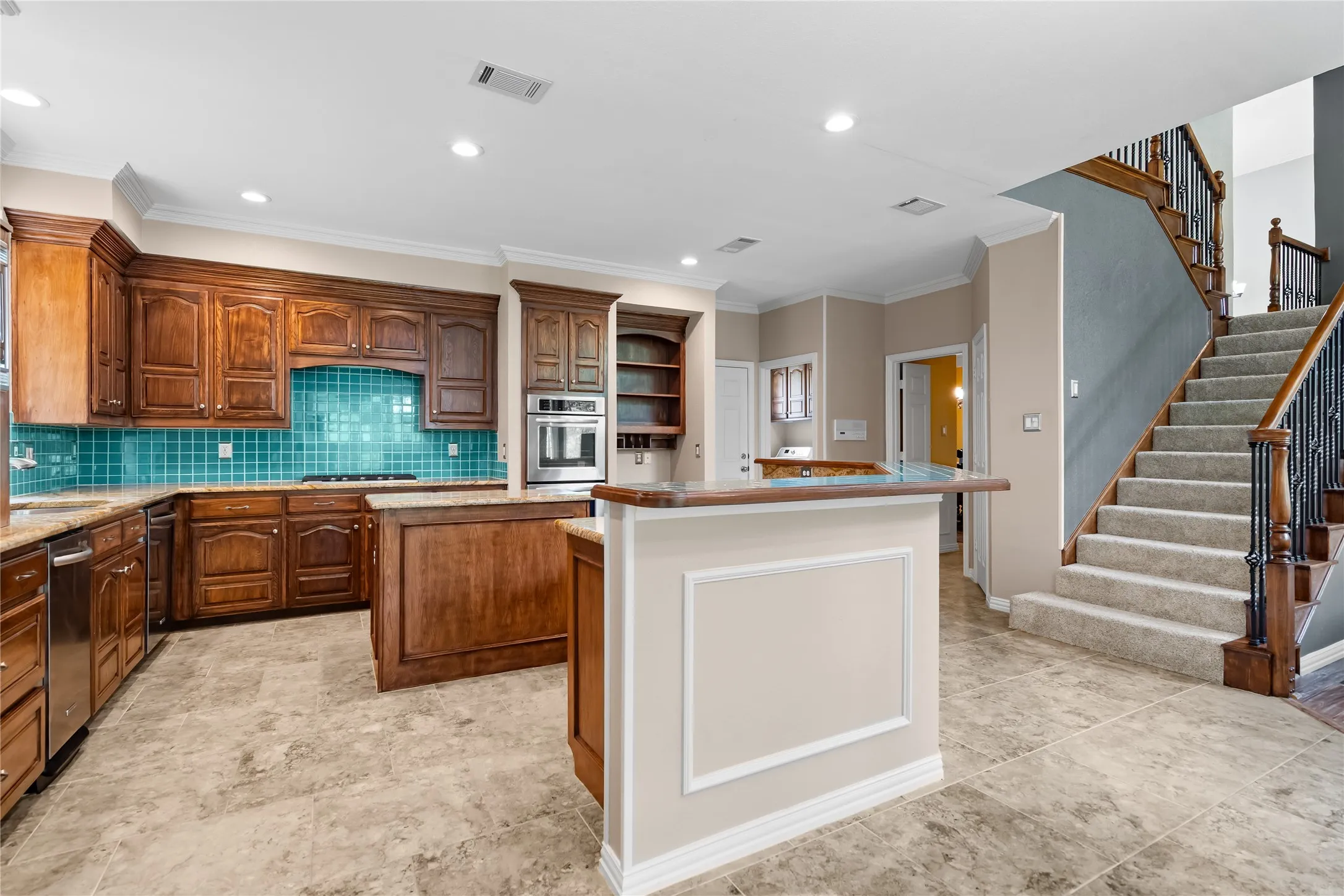 Kitchen featuring warm wood cabinetry, a turquoise tile backsplash, stainless steel appliances, and stone-look flooring