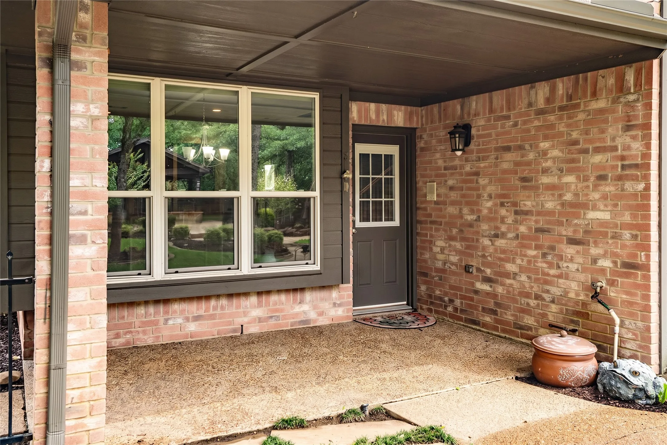 Covered patio entry with brick facade and multi-pane windows