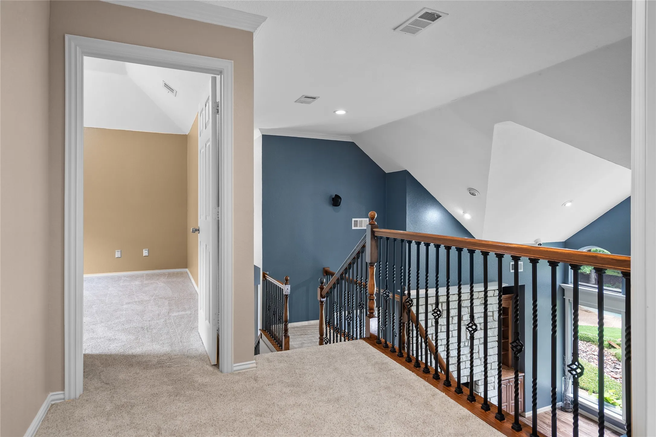 Carpeted hallway featuring a white door opening to a room with sloped ceilings and light beige walls