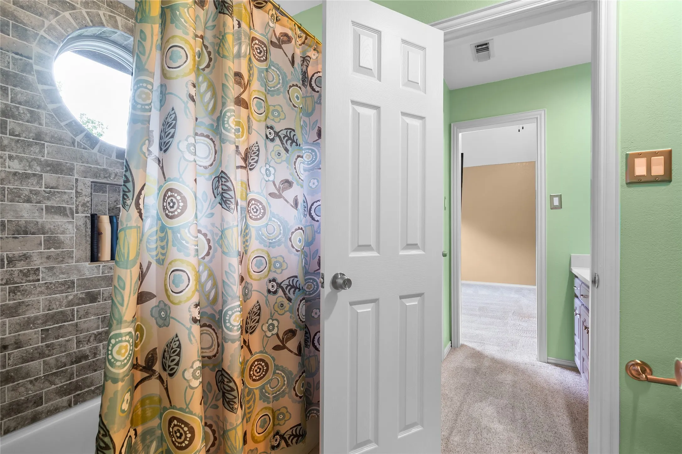Bathroom featuring a round window, subway tile shower surround, and built-in shower niche